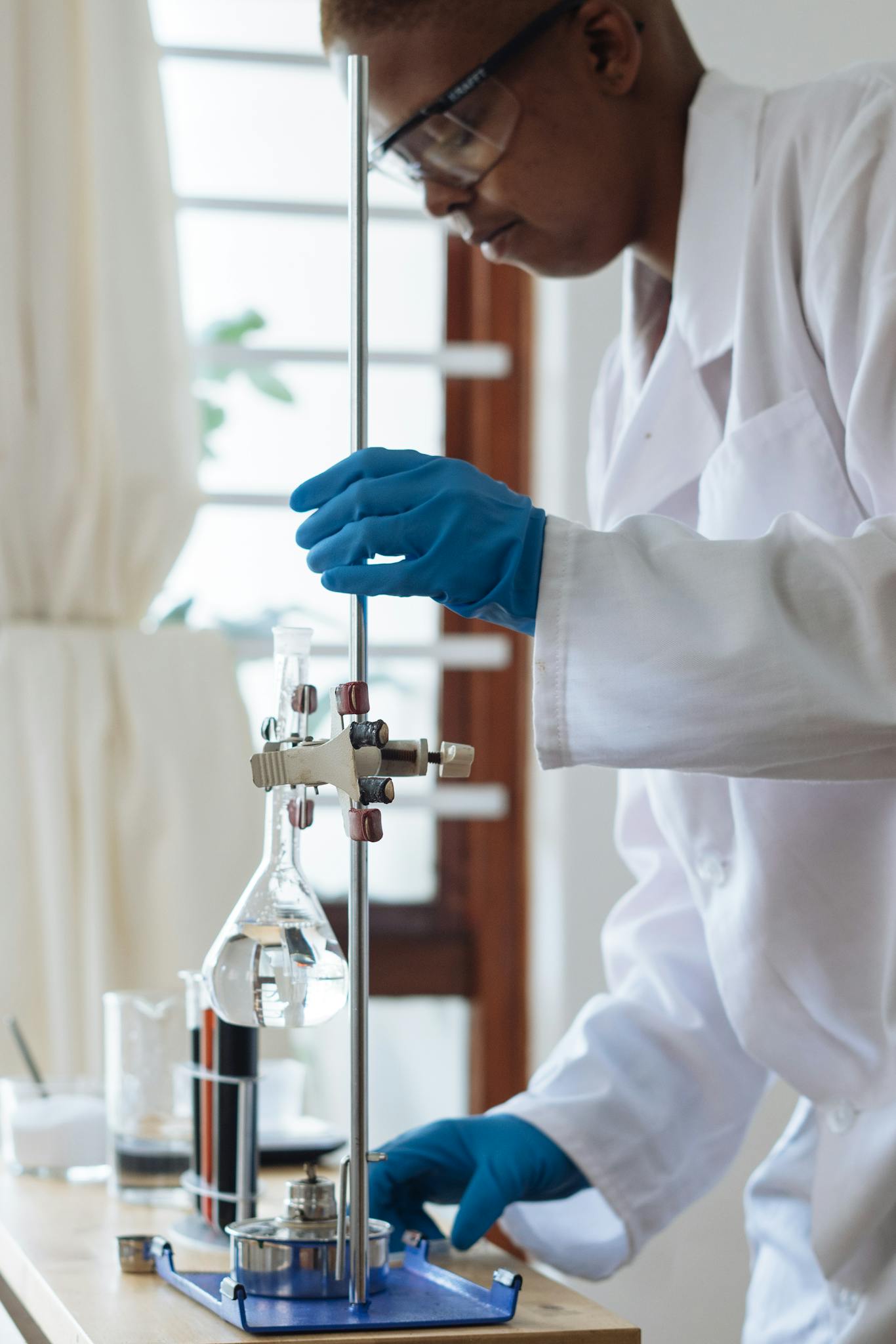 Professional scientist wearing a lab coat and gloves conducting an experiment with glassware indoors.